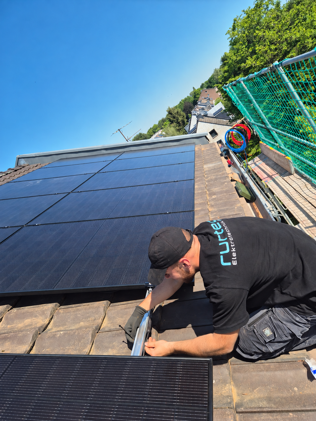 Mitarbeiter von rurtec bei der Montage von Photovoltaik-Modulen auf einem Ziegeldach